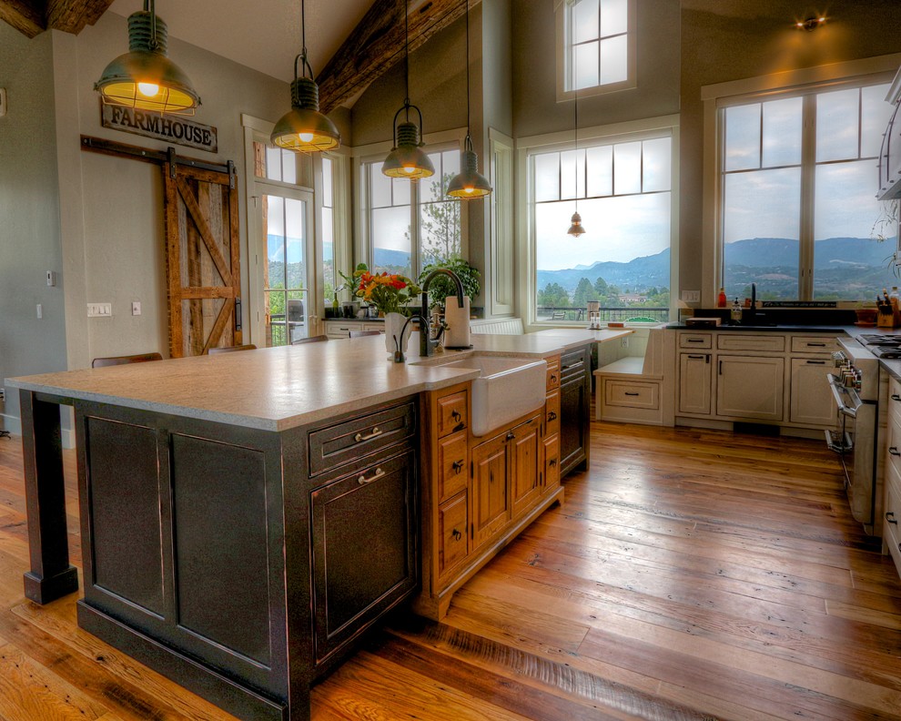 Photo of a large country l-shaped kitchen in Denver with a farmhouse sink, black cabinets, granite benchtops, light hardwood floors, with island, brown floor, white benchtop and beaded inset cabinets.