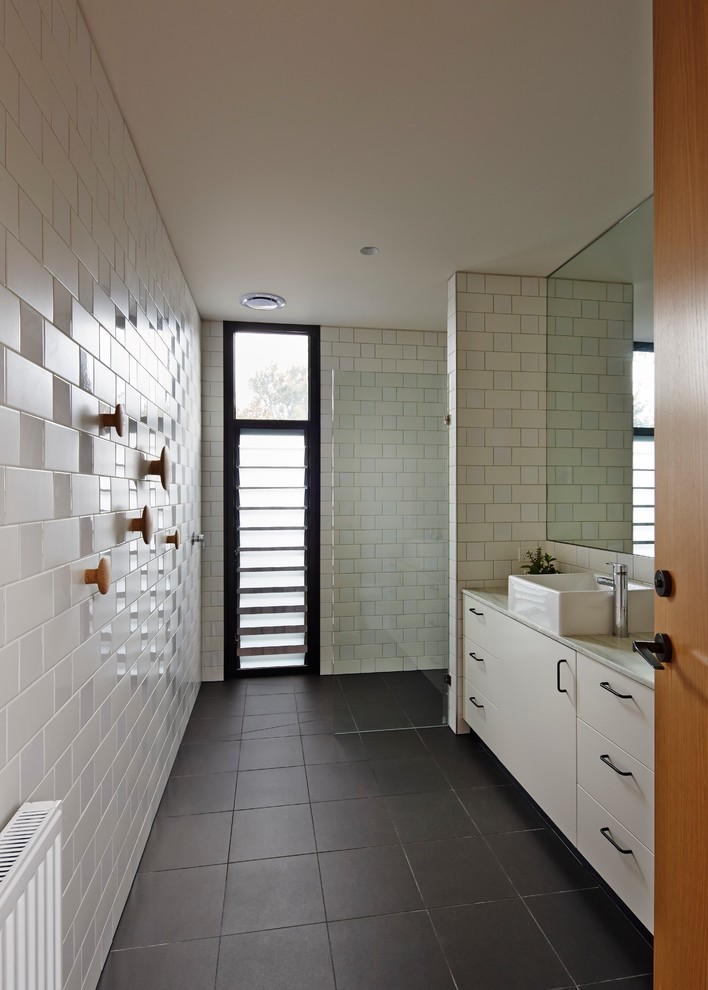This is an example of a mid-sized contemporary master bathroom in Melbourne with a trough sink, furniture-like cabinets, white cabinets and an open shower.