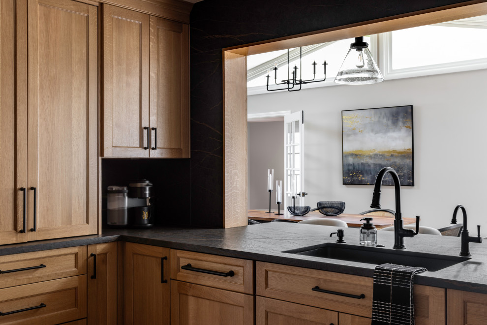 Example of a large mountain style galley medium tone wood floor enclosed kitchen design in DC Metro with an undermount sink, recessed-panel cabinets, medium tone wood cabinets, quartz countertops, black backsplash, quartz backsplash, stainless steel appliances, no island and black countertops