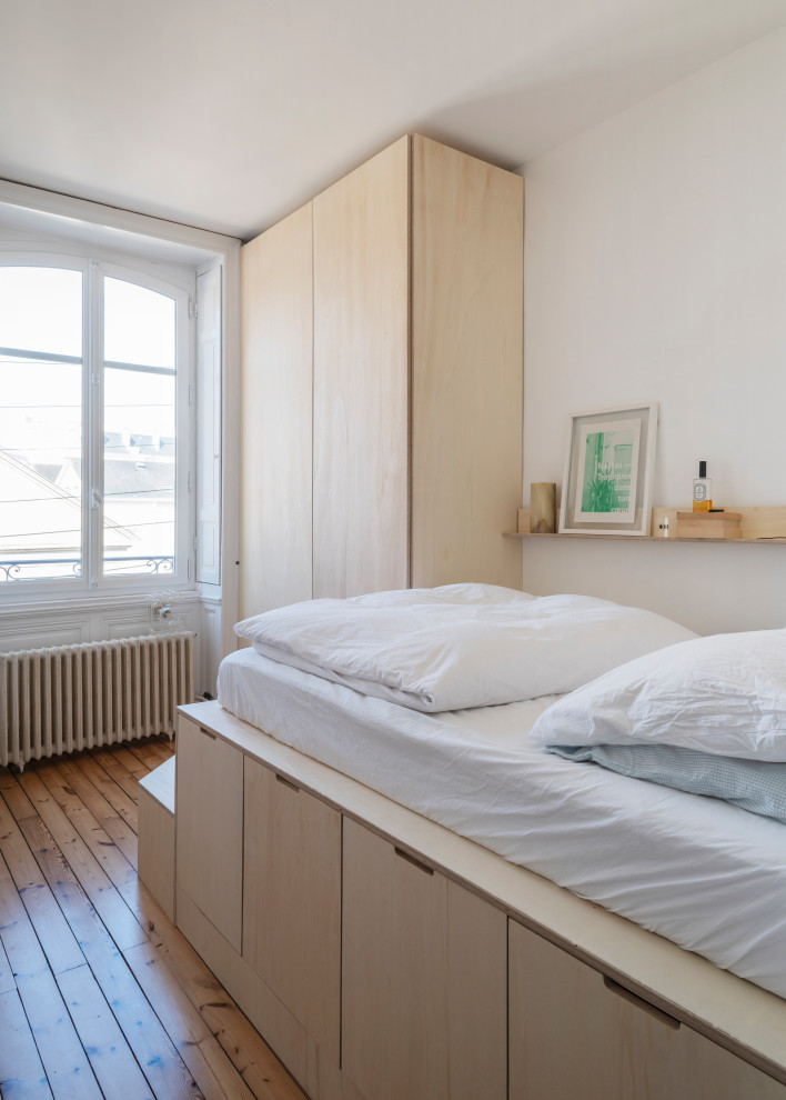 На фото: маленькая хозяйская спальня в белых тонах с отделкой деревом в скандинавском стиле с белыми стенами, паркетным полом среднего тона и панелями на стенах для на участке и в саду
