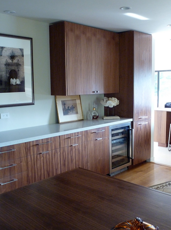 This is an example of a mid-sized modern single-wall wet bar in San Francisco with no sink, flat-panel cabinets, medium wood cabinets and light hardwood floors.