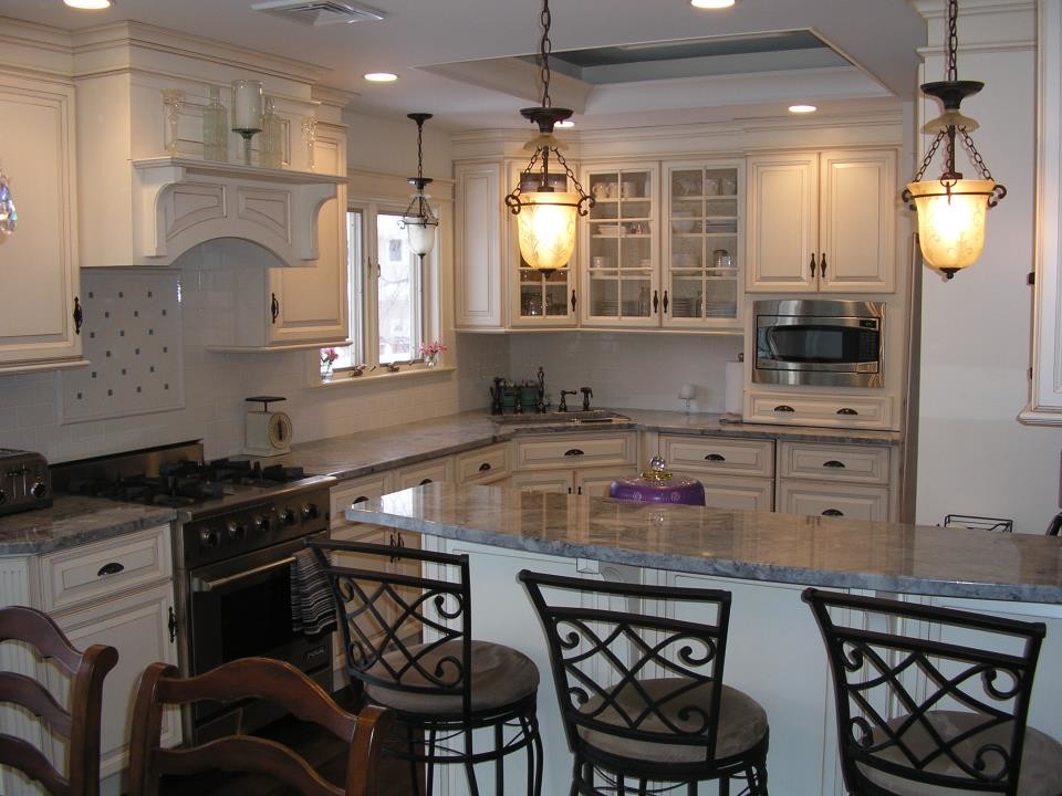 This is an example of a large traditional u-shaped eat-in kitchen in New York with an undermount sink, raised-panel cabinets, white cabinets, quartzite benchtops, white splashback, subway tile splashback, stainless steel appliances, dark hardwood floors and a peninsula.