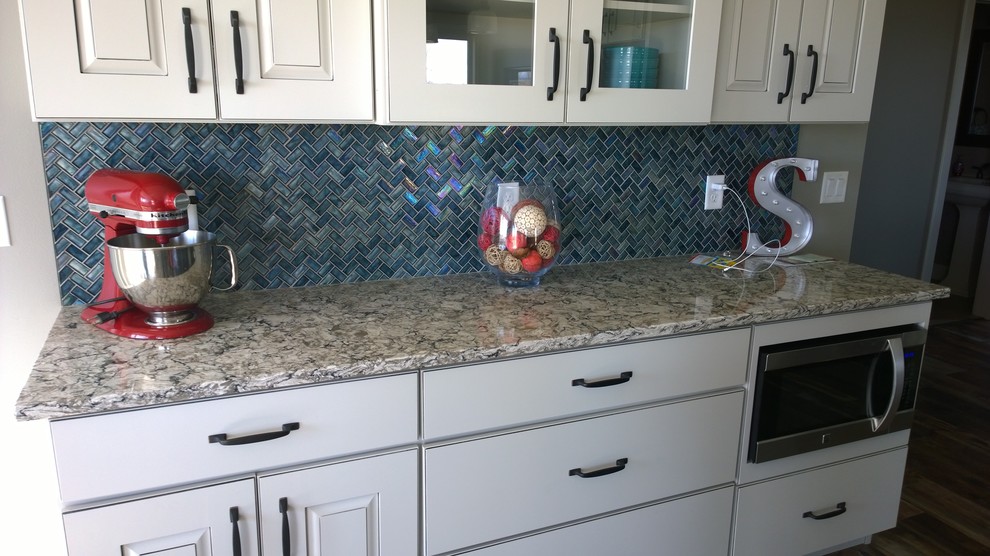 Large minimalist eat-in kitchen photo with white cabinets, blue backsplash, glass tile backsplash, stainless steel appliances and an island