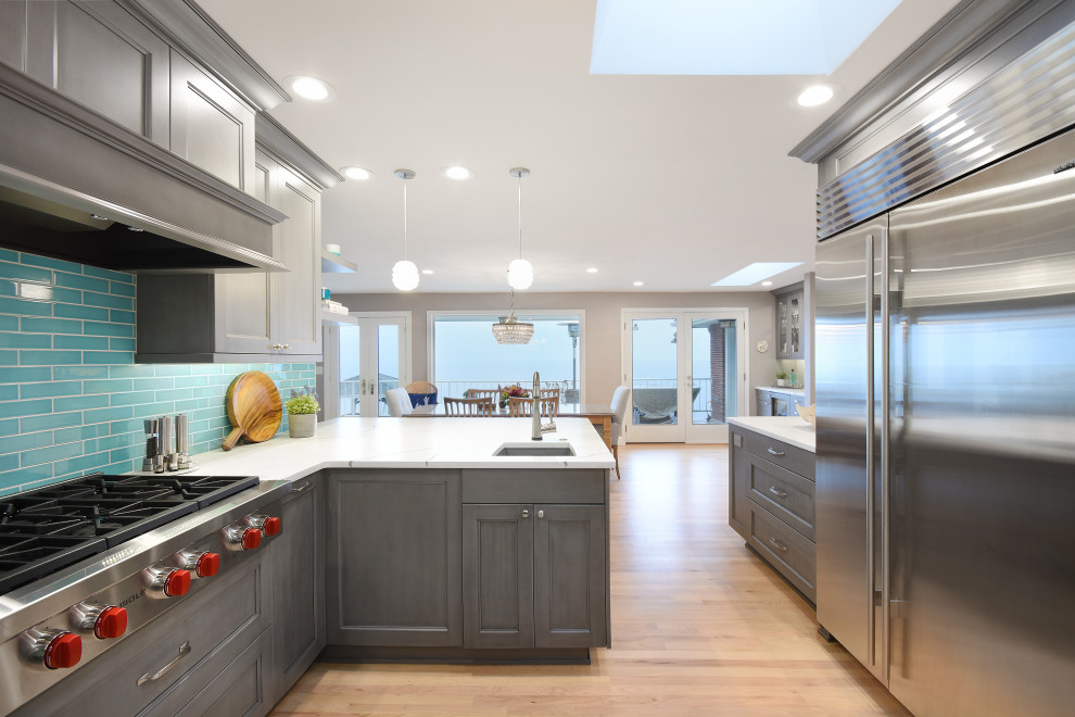 Large transitional eat-in kitchen in Seattle with a farmhouse sink, recessed-panel cabinets, grey cabinets, quartz benchtops, blue splashback, ceramic splashback, stainless steel appliances, light hardwood floors, a peninsula, yellow floor and white benchtop.