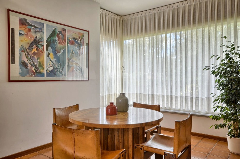 Esempio di una piccola sala da pranzo aperta verso il soggiorno moderna con pareti bianche, pavimento in terracotta e pavimento marrone