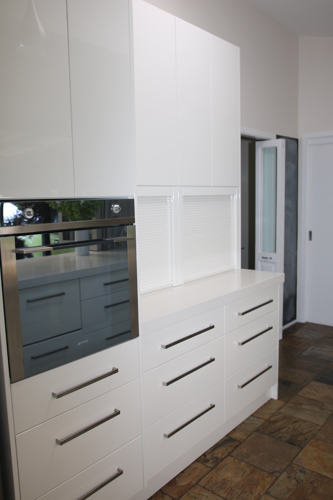 Inspiration for a large modern galley kitchen pantry in Sydney with an undermount sink, flat-panel cabinets, white cabinets, quartz benchtops, brown splashback, glass sheet splashback, stainless steel appliances, slate floors and no island.