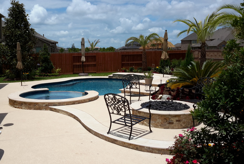 Photo of a mid-sized traditional backyard custom-shaped natural pool in Houston with a hot tub and decking.