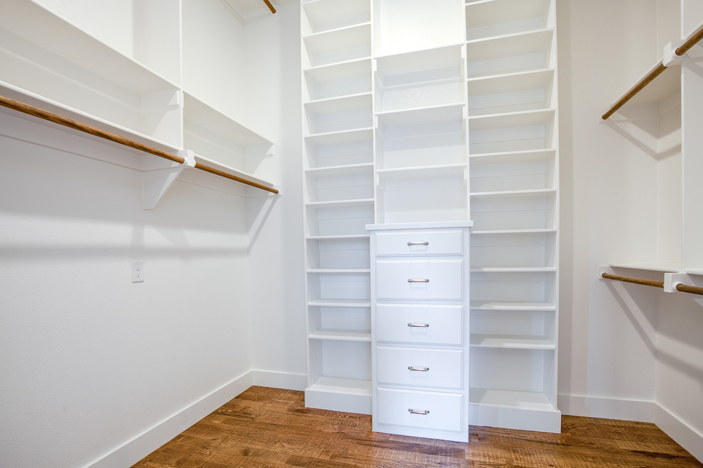 Large country gender-neutral walk-in wardrobe in Dallas with louvered cabinets, white cabinets, medium hardwood floors and brown floor.