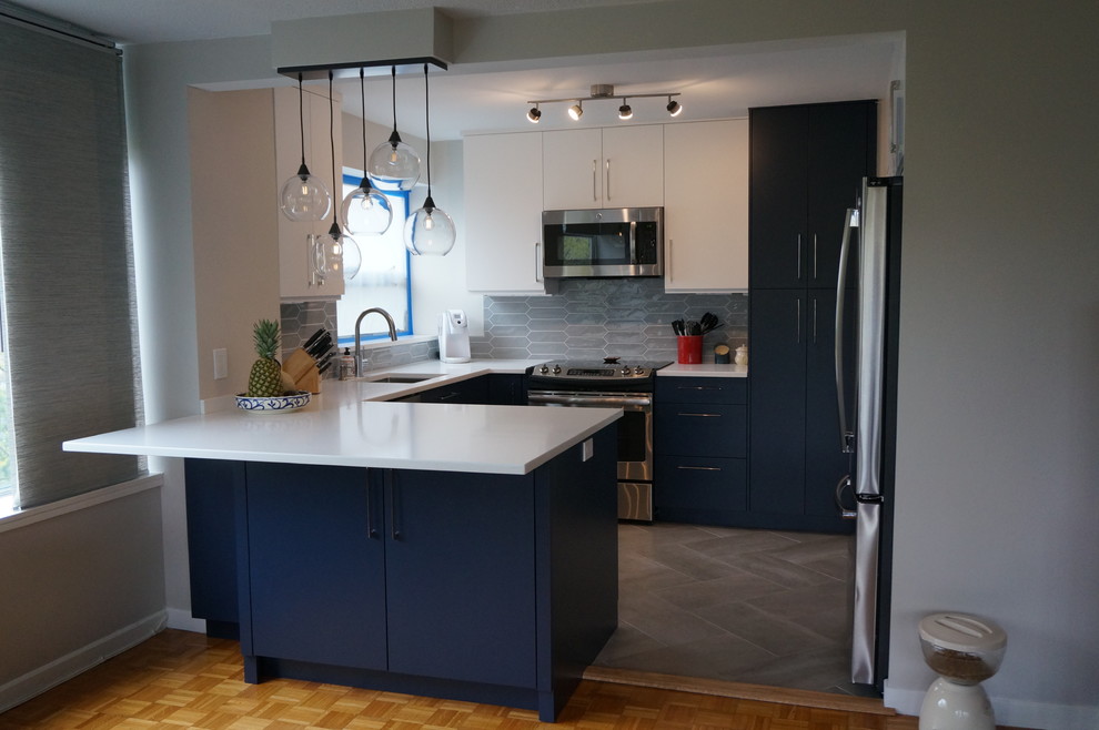 Small contemporary u-shaped eat-in kitchen in Boston with a drop-in sink, flat-panel cabinets, blue cabinets, quartz benchtops, grey splashback, glass tile splashback, stainless steel appliances, a peninsula and grey floor.
