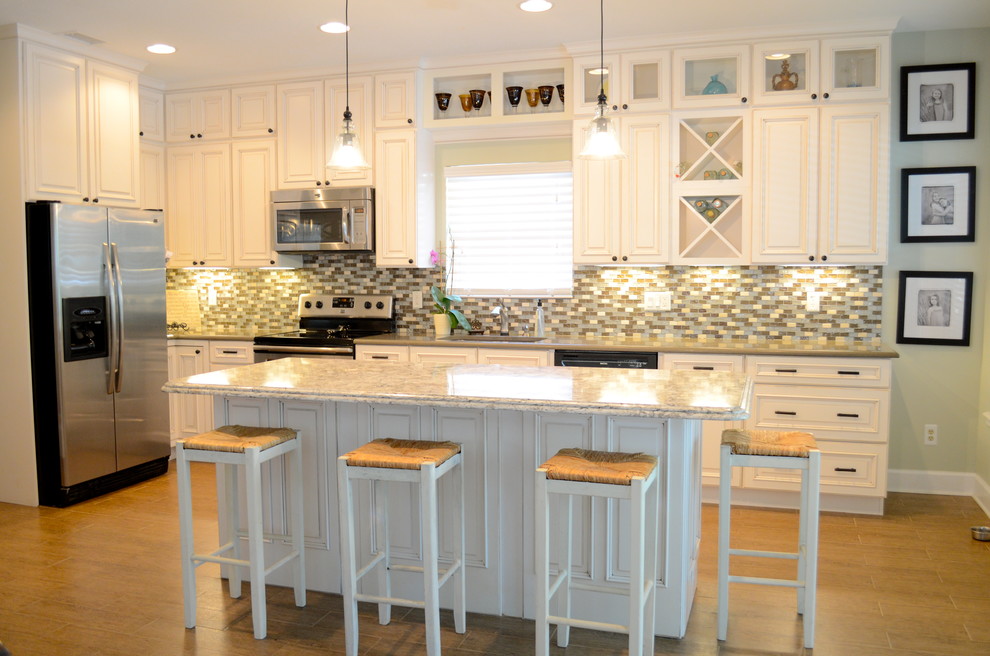 Photo of a mid-sized beach style single-wall open plan kitchen in Jacksonville with an undermount sink, raised-panel cabinets, beige cabinets, quartzite benchtops, stainless steel appliances, porcelain floors and with island.