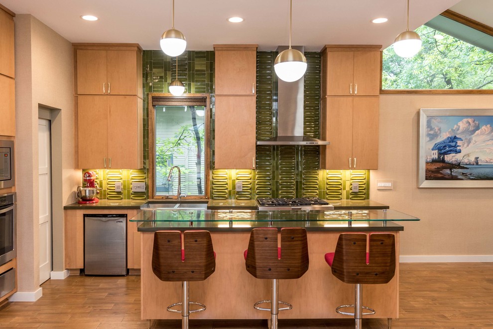 Photo of a mid-sized midcentury kitchen in Austin with flat-panel cabinets, light wood cabinets, quartz benchtops, green splashback, porcelain splashback, stainless steel appliances, ceramic floors, with island and a double-bowl sink.
