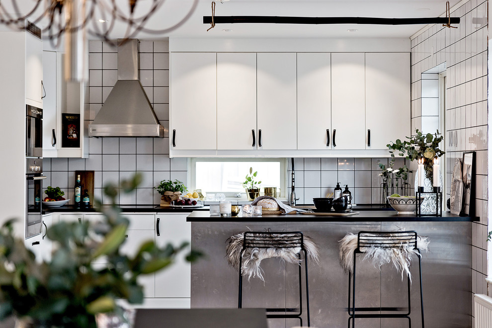 Photo of a mid-sized industrial single-wall kitchen in Orebro with flat-panel cabinets, white cabinets, white splashback, ceramic splashback, white appliances and with island.