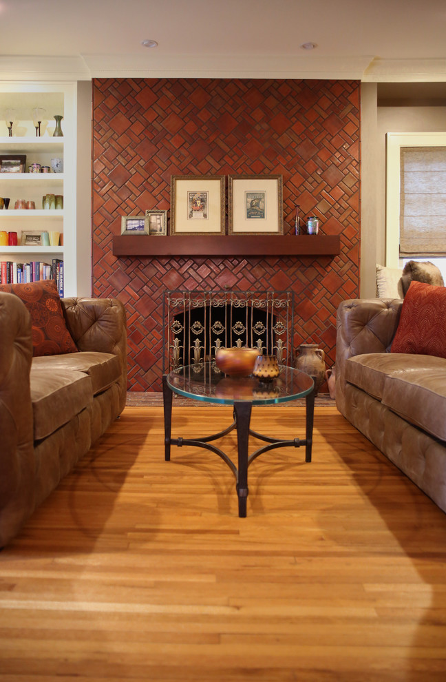 Inspiration for a mid-sized arts and crafts enclosed living room in Detroit with orange walls, light hardwood floors, a standard fireplace, a tile fireplace surround, no tv, a library and brown floor.