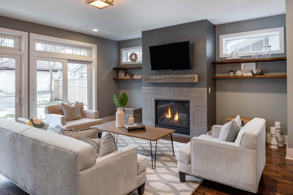 Design ideas for a mid-sized transitional open concept family room in Minneapolis with grey walls, medium hardwood floors, a standard fireplace, a tile fireplace surround and a wall-mounted tv.