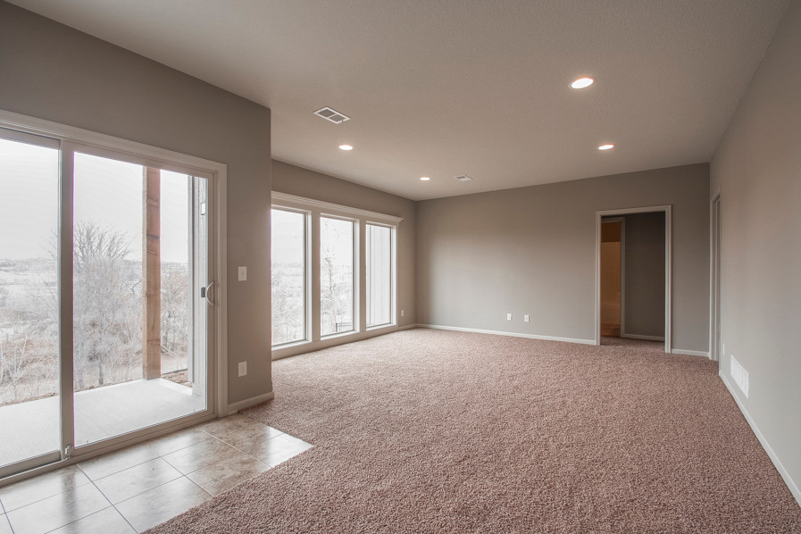 Large traditional walk-out basement in Kansas City with grey walls, carpet and pink floor.