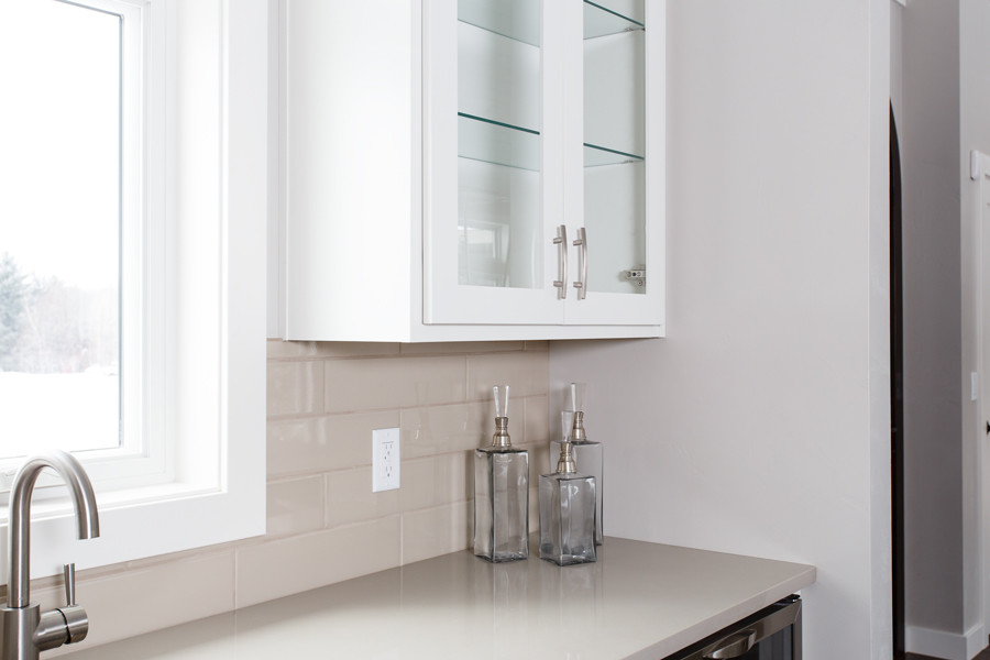 Transitional kitchen photo with glass-front cabinets, white cabinets, soapstone countertops, white backsplash, subway tile backsplash and stainless steel appliances