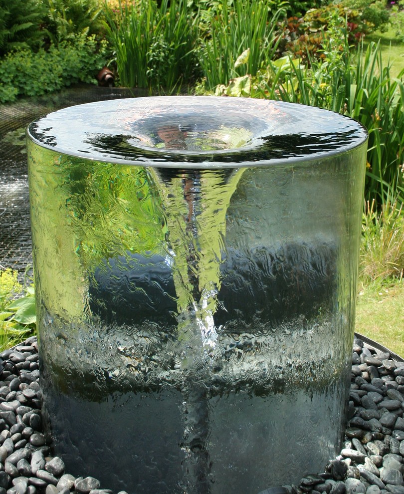 Inspiration for a large modern backyard partial sun garden in London with a water feature.