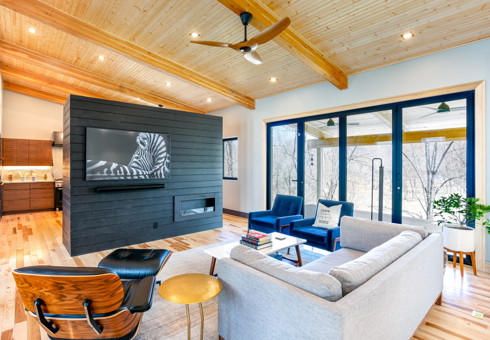 This is an example of a mid-sized contemporary open concept living room in Kansas City with grey walls, medium hardwood floors, a ribbon fireplace, a built-in media wall and exposed beam.