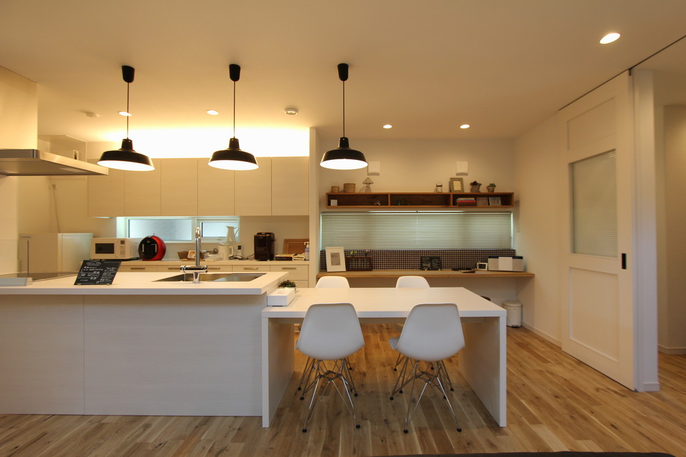 Country galley eat-in kitchen in Tokyo with an undermount sink, flat-panel cabinets, medium wood cabinets, onyx benchtops, stainless steel appliances, light hardwood floors, multiple islands and beige floor.