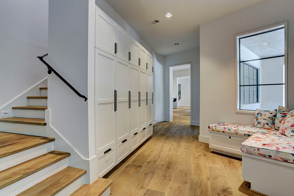 This is an example of a transitional hallway in Houston with white walls, medium hardwood floors and brown floor.