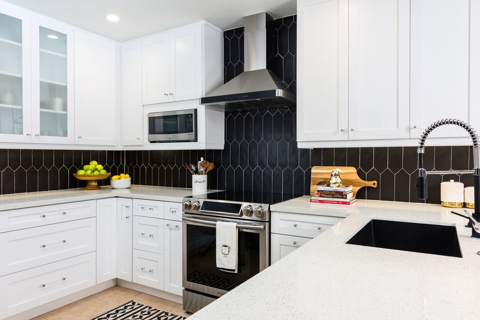 Photo of a mid-sized contemporary l-shaped separate kitchen in Other with a drop-in sink, shaker cabinets, white cabinets, quartz benchtops, black splashback, ceramic splashback, stainless steel appliances, porcelain floors, with island, beige floor and white benchtop.