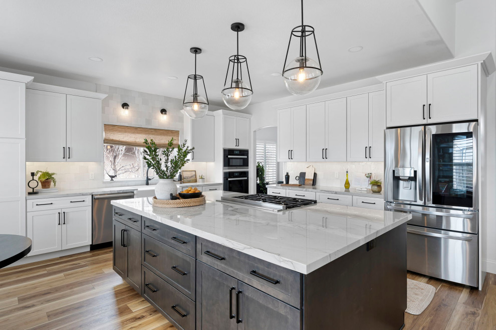 Transitional vinyl floor and brown floor kitchen photo with a farmhouse sink, shaker cabinets, white cabinets, quartzite countertops, white backsplash and stainless steel appliances