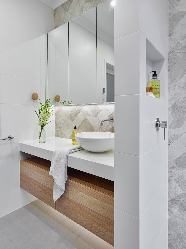 This is an example of a small contemporary 3/4 bathroom in Other with light wood cabinets, an open shower, a two-piece toilet, gray tile, white walls, ceramic floors, a vessel sink, engineered quartz benchtops, limestone, grey floor, an open shower and white benchtops.