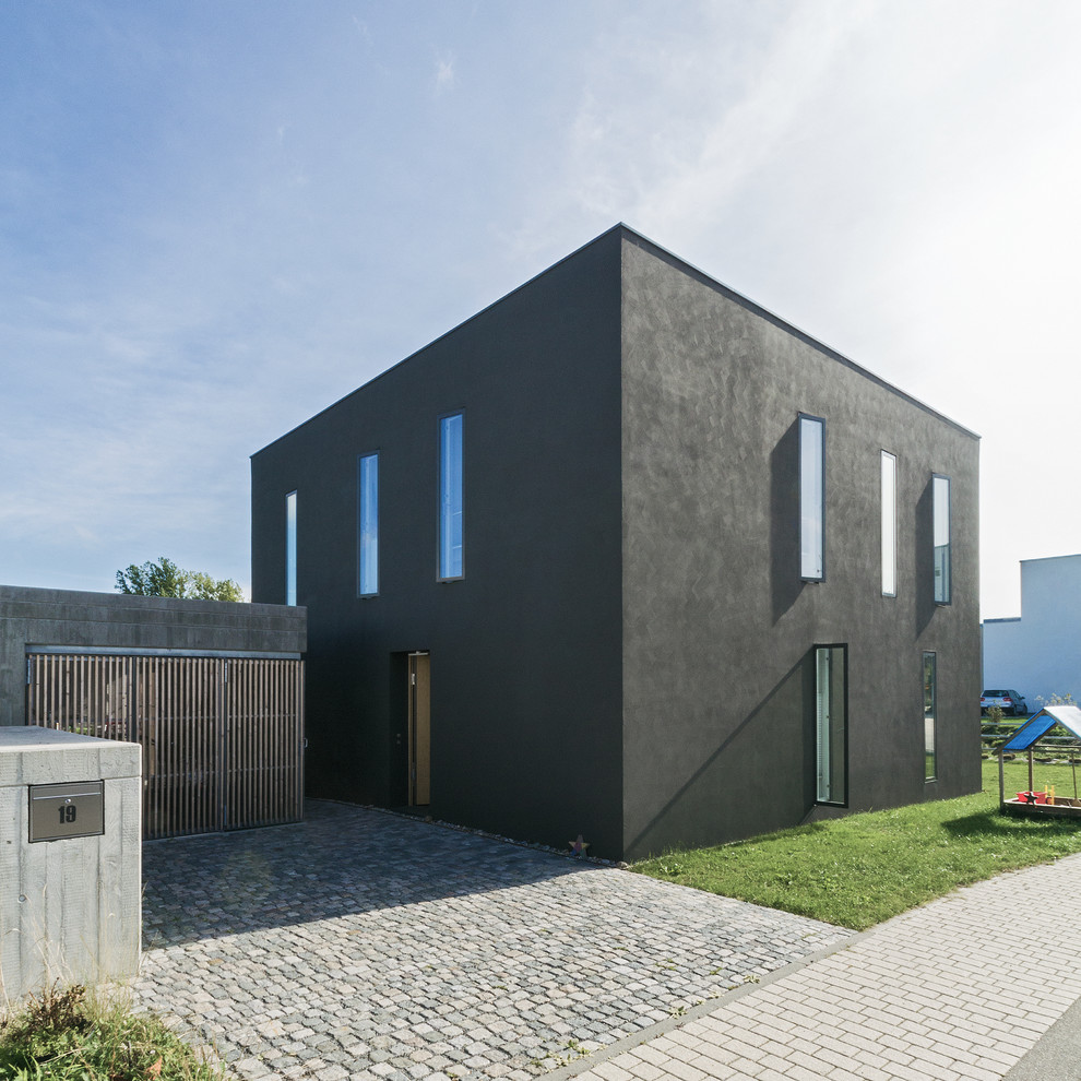Mid-sized modern two-storey stucco grey house exterior in Stuttgart with a flat roof.