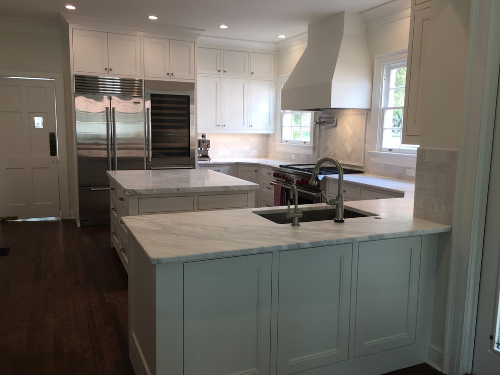 Design ideas for a large transitional u-shaped separate kitchen in Austin with an undermount sink, recessed-panel cabinets, white cabinets, marble benchtops, white splashback, marble splashback, stainless steel appliances, dark hardwood floors, with island, brown floor and white benchtop.