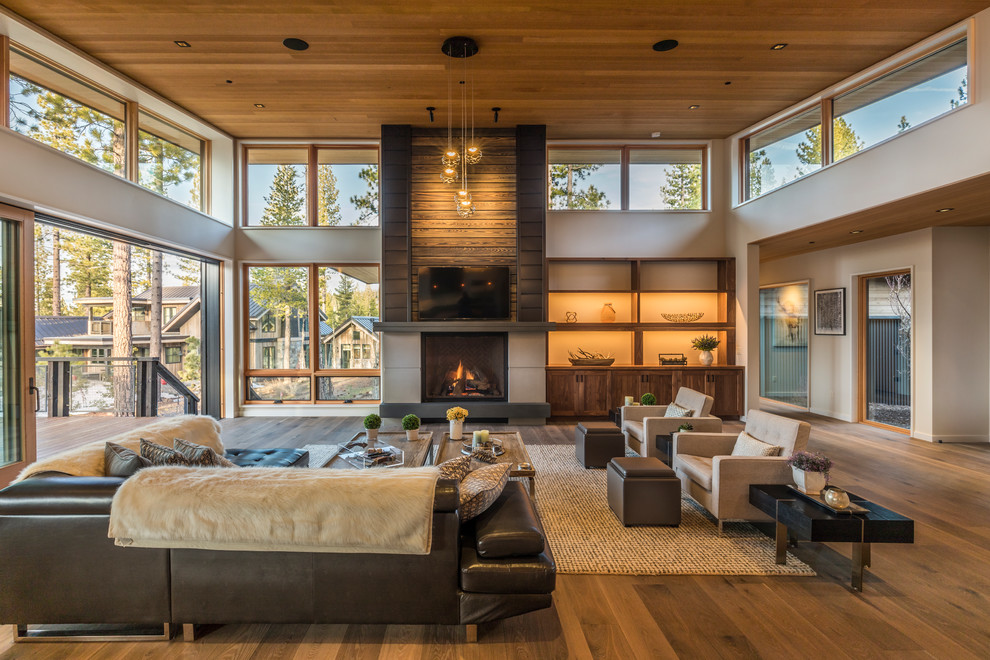 This is an example of a country open concept living room in Sacramento with medium hardwood floors, a standard fireplace, a wall-mounted tv and grey walls.