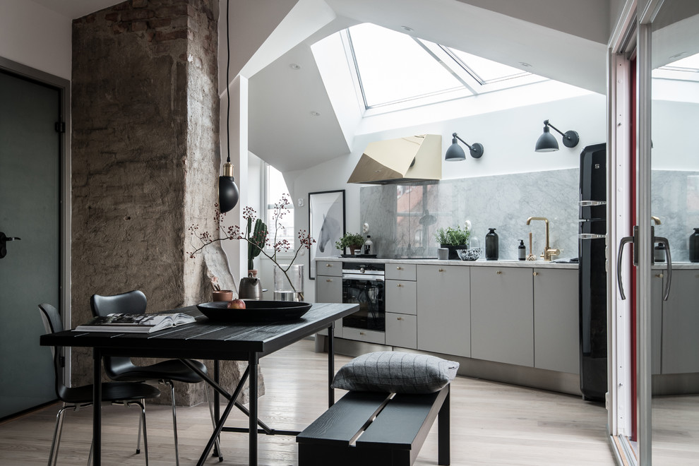 This is an example of a large scandinavian single-wall open plan kitchen in Gothenburg with a single-bowl sink, flat-panel cabinets, white cabinets, marble benchtops, grey splashback, light hardwood floors and no island.