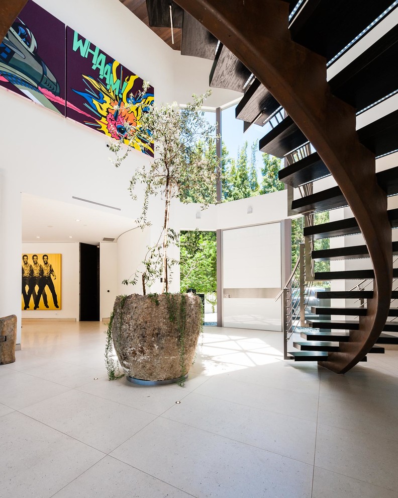 Photo of an expansive contemporary foyer in Los Angeles with white walls, concrete floors, a pivot front door, a white front door and grey floor.