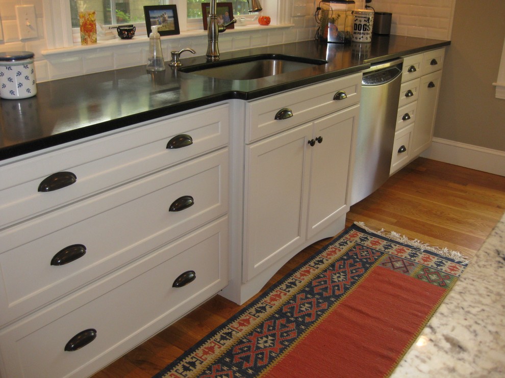 Eat-in kitchen - transitional l-shaped medium tone wood floor eat-in kitchen idea in Boston with an undermount sink, shaker cabinets, white cabinets, granite countertops, white backsplash, ceramic backsplash, stainless steel appliances, an island and black countertops