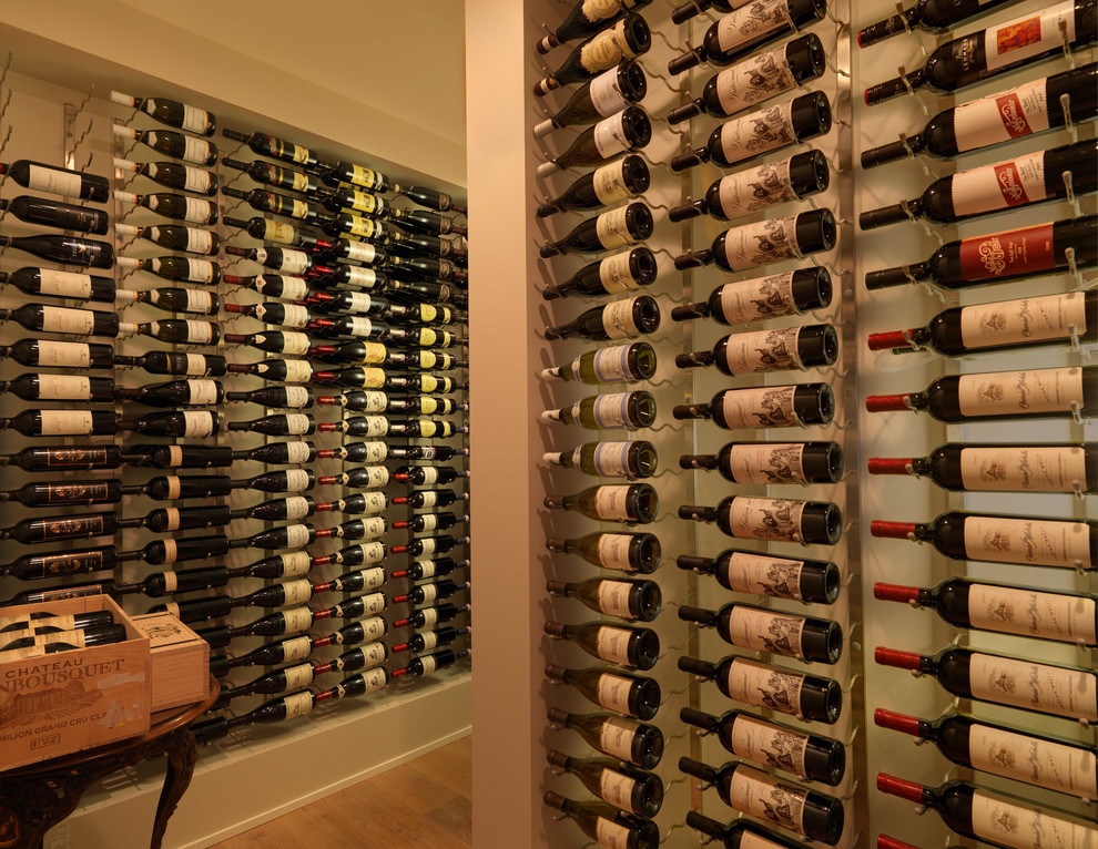 This is an example of a mid-sized modern wine cellar in Vancouver with display racks, light hardwood floors and brown floor.