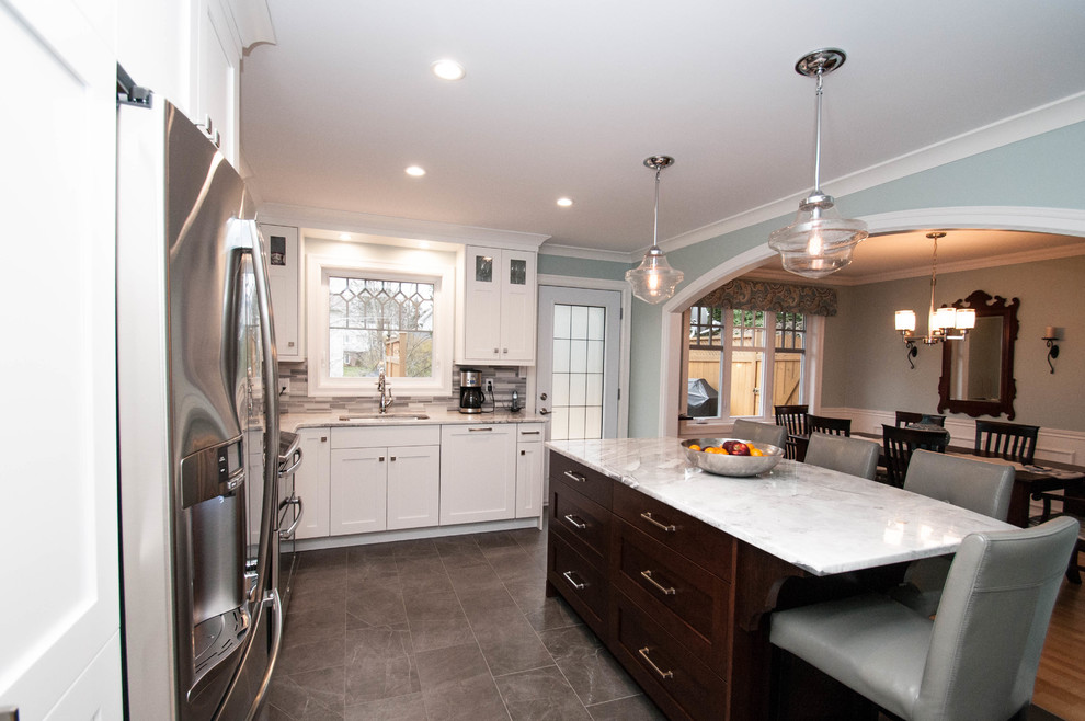 Mid-sized transitional l-shaped ceramic tile and gray floor eat-in kitchen photo with an undermount sink, shaker cabinets, white cabinets, quartzite countertops, gray backsplash, stone tile backsplash, stainless steel appliances and an island
