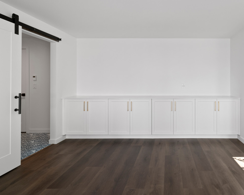 Inspiration for a large transitional single-wall vinyl floor, brown floor and vaulted ceiling open concept kitchen remodel in Seattle with an undermount sink, shaker cabinets, white cabinets, quartz countertops, white backsplash, quartz backsplash, stainless steel appliances, an island and white countertops