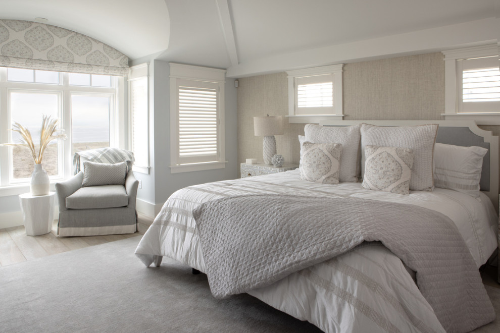 Diseño de dormitorio principal y abovedado marinero grande con paredes azules, suelo de madera clara y papel pintado