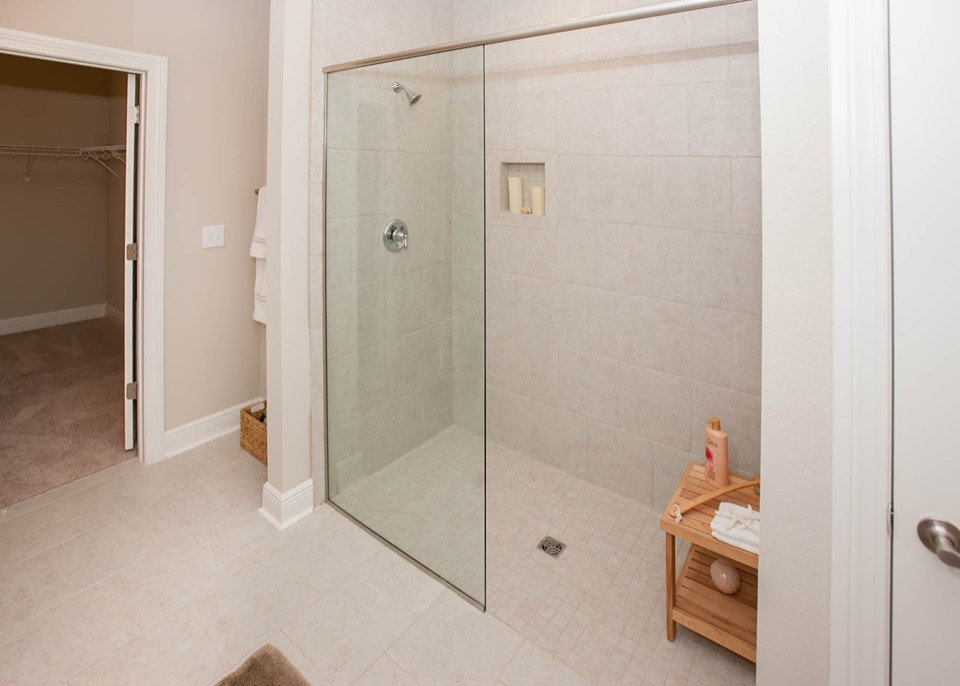 Photo of a mid-sized beach style master bathroom in Other with shaker cabinets, white cabinets, a curbless shower, a two-piece toilet, beige tile, ceramic tile, beige walls, ceramic floors, an undermount sink, granite benchtops, beige floor, an open shower and beige benchtops.