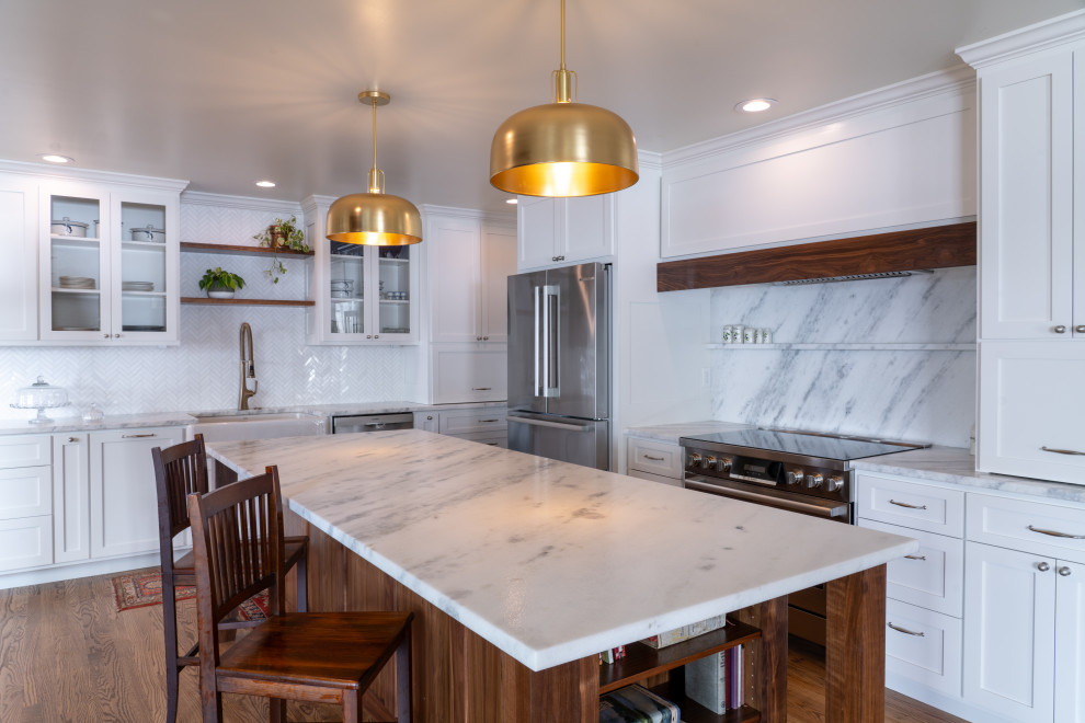 This is an example of a large transitional l-shaped eat-in kitchen in Other with a farmhouse sink, shaker cabinets, white cabinets, marble benchtops, stone tile splashback, stainless steel appliances, plywood floors, with island, brown floor and white benchtop.
