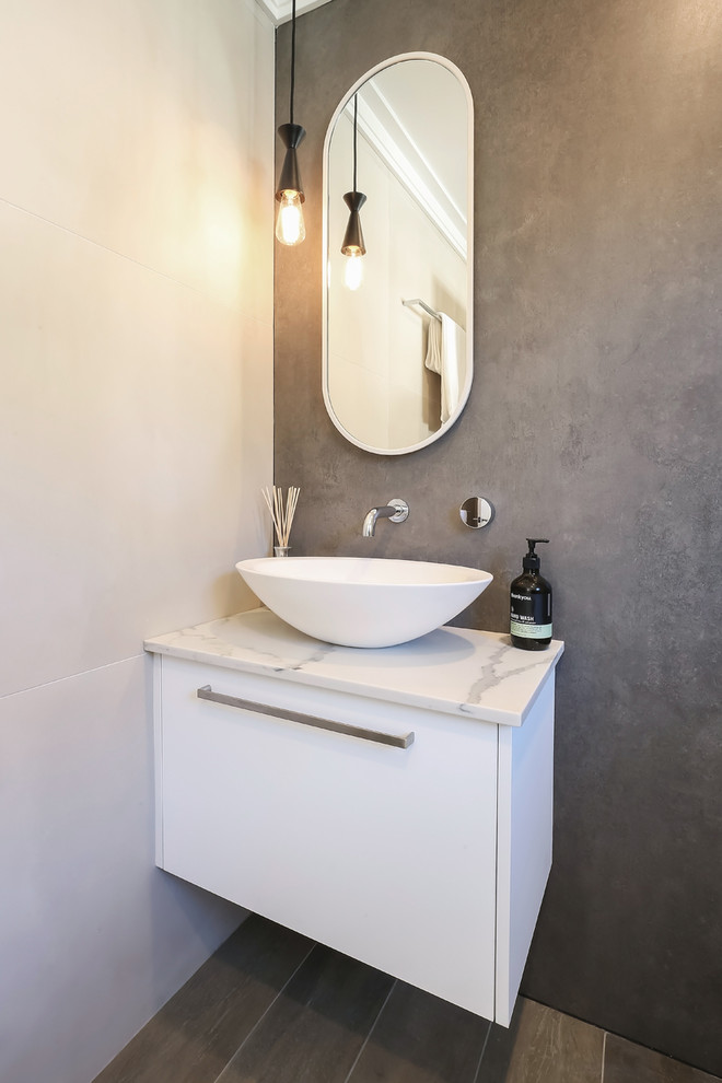 This is an example of a small contemporary 3/4 bathroom in Sydney with flat-panel cabinets, white cabinets, a corner shower, a wall-mount toilet, brown tile, porcelain tile, beige walls, porcelain floors, a vessel sink, engineered quartz benchtops, brown floor, an open shower and white benchtops.