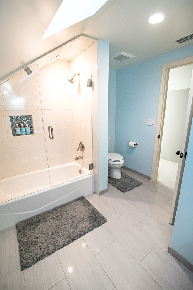 This is an example of a mid-sized transitional 3/4 bathroom in Orange County with shaker cabinets, white cabinets, an alcove tub, a shower/bathtub combo, a two-piece toilet, gray tile, ceramic tile, blue walls, ceramic floors, an undermount sink and engineered quartz benchtops.