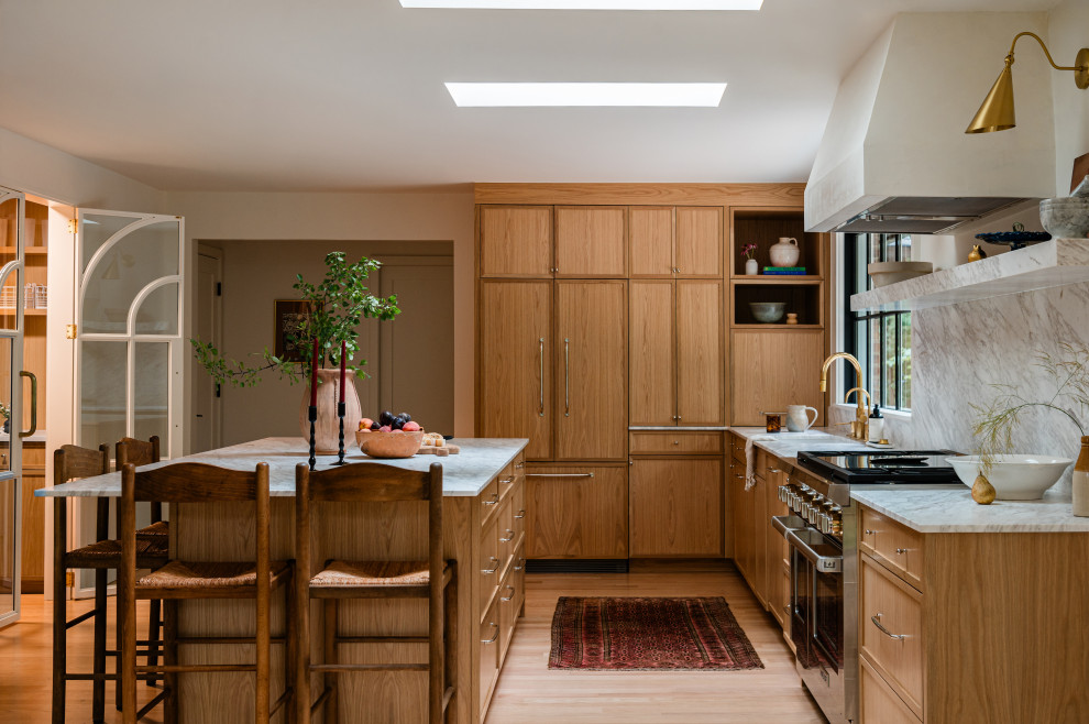 Example of a mid-sized transitional l-shaped light wood floor eat-in kitchen design in Chicago with an undermount sink, shaker cabinets, light wood cabinets, marble countertops, white backsplash, marble backsplash, paneled appliances, an island and white countertops