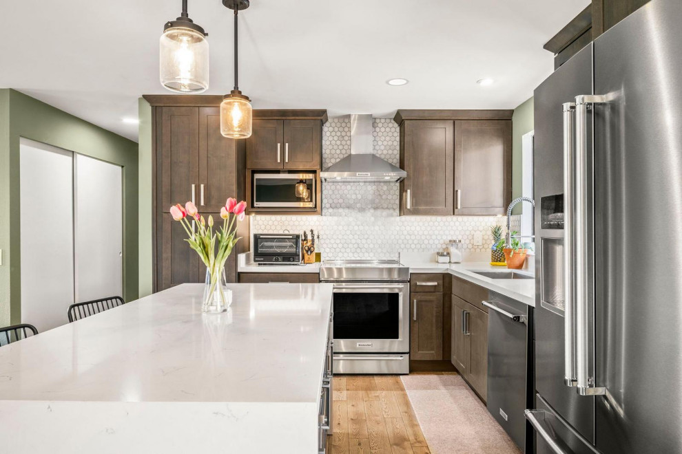 Large midcentury l-shaped kitchen in Seattle with shaker cabinets, dark wood cabinets, marble benchtops, mosaic tile splashback, stainless steel appliances and with island.