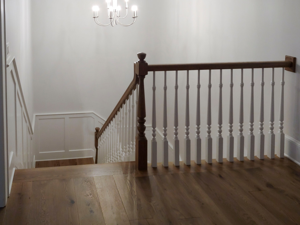 На фото: п-образная лестница среднего размера в классическом стиле с деревянными ступенями, крашенными деревянными подступенками, деревянными перилами и панелями на стенах с