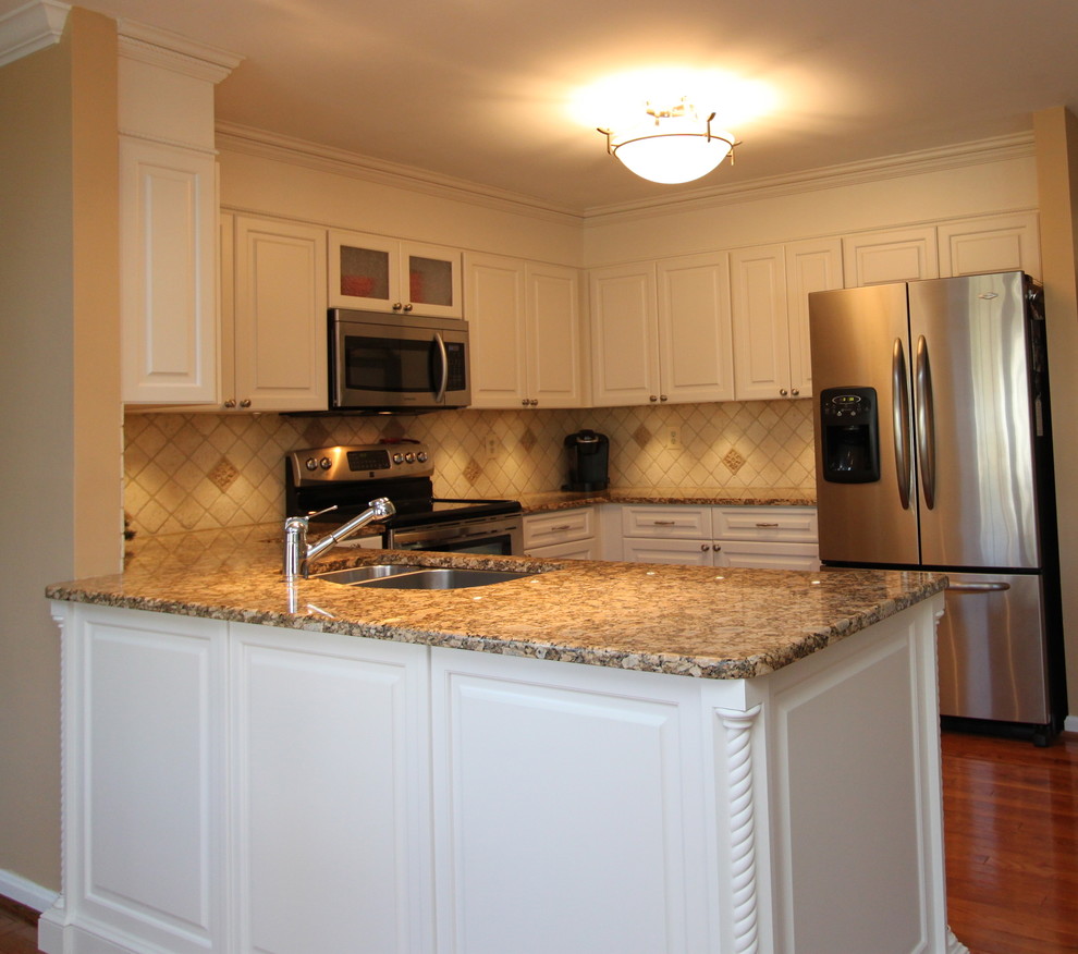 Photo of a transitional u-shaped eat-in kitchen in Baltimore with an undermount sink, raised-panel cabinets, white cabinets, granite benchtops, stainless steel appliances, medium hardwood floors, a peninsula, beige splashback and ceramic splashback.