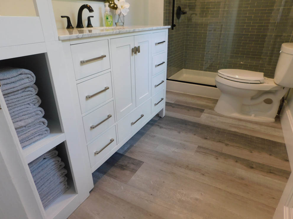 Photo of a mid-sized transitional kids bathroom in Cincinnati with shaker cabinets, white cabinets, an alcove shower, a two-piece toilet, gray tile, glass tile, grey walls, vinyl floors, an undermount sink, marble benchtops, grey floor, a sliding shower screen, grey benchtops and a single vanity.