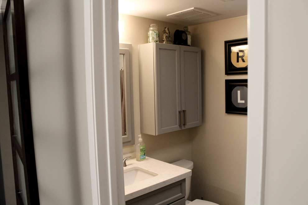 Small trendy master white tile porcelain tile and brown floor walk-in shower photo with recessed-panel cabinets, gray cabinets, a one-piece toilet, yellow walls, an undermount sink, quartz countertops and white countertops