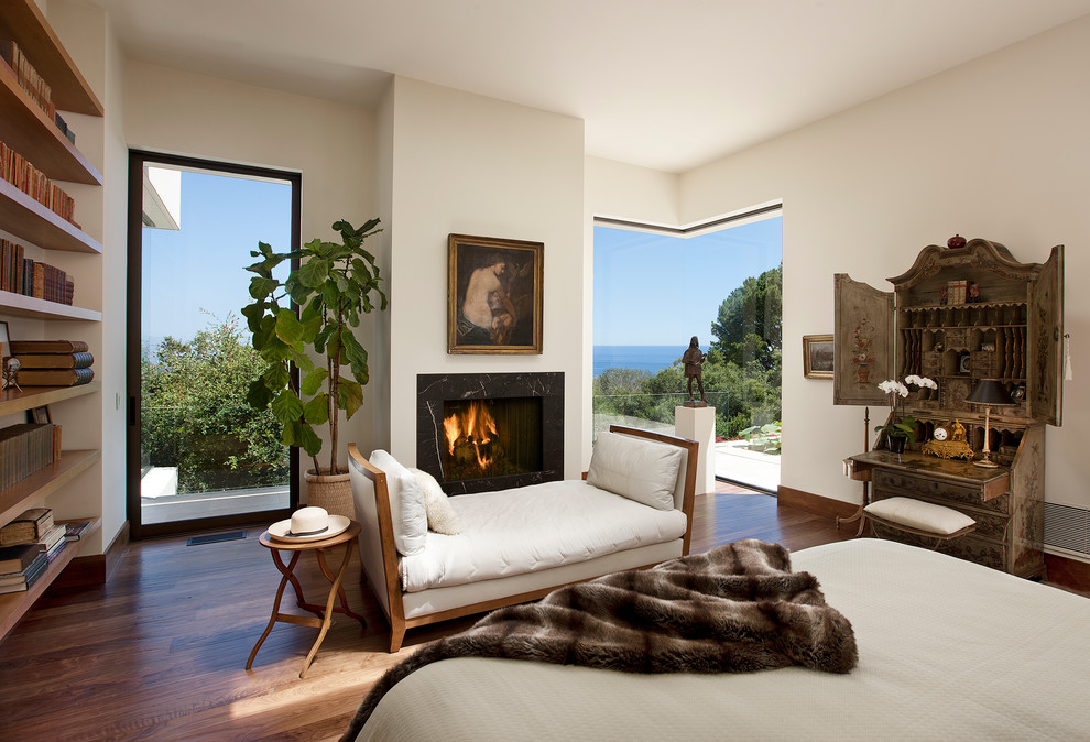 Photo of a large mediterranean master bedroom in Santa Barbara with white walls, a stone fireplace surround, a ribbon fireplace and medium hardwood floors.