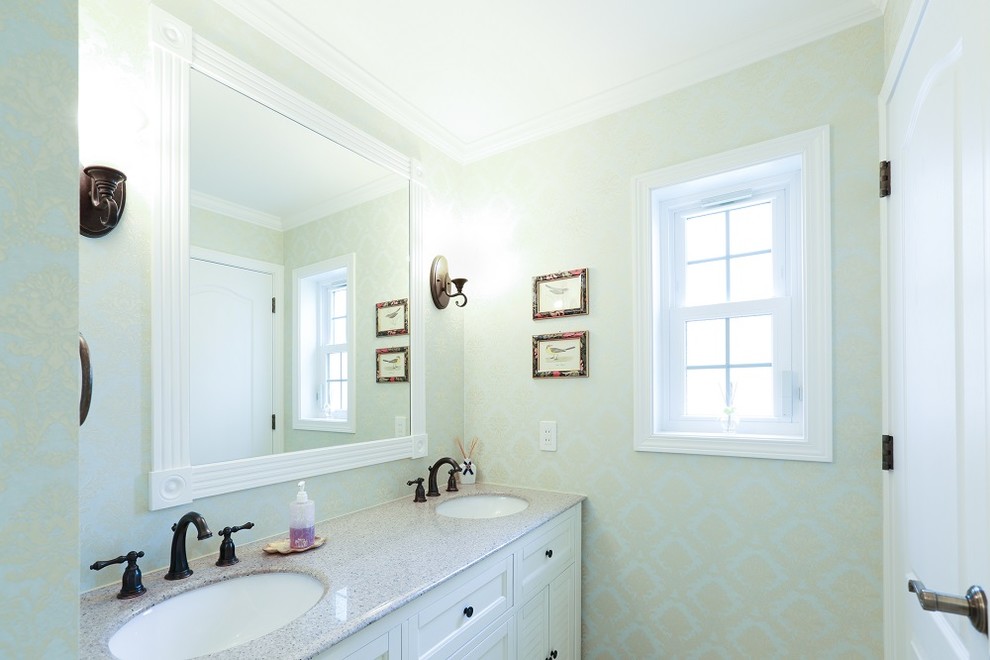 Photo of a large traditional powder room in Other with furniture-like cabinets, white cabinets, green walls, vinyl floors, a drop-in sink, solid surface benchtops and white floor.