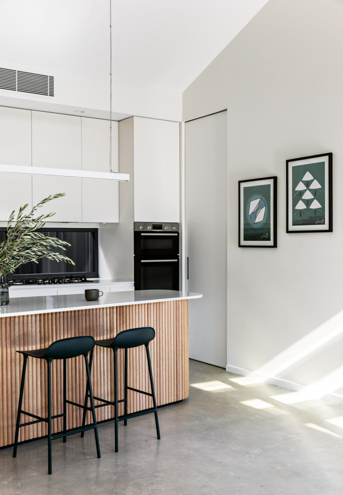 Design ideas for a mid-sized modern galley eat-in kitchen in Sydney with an undermount sink, flat-panel cabinets, white cabinets, quartzite benchtops, window splashback, stainless steel appliances, concrete floors, with island, grey floor and white benchtop.